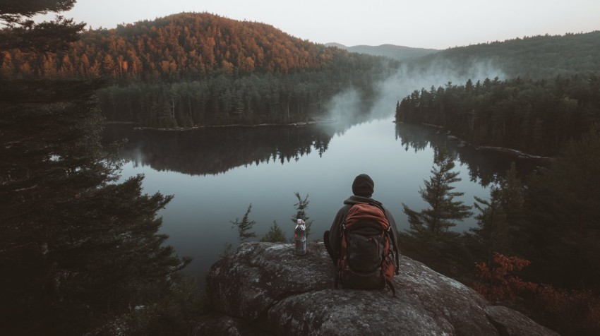 Cliff Edge with Misty Lake and Backpack at Dawn